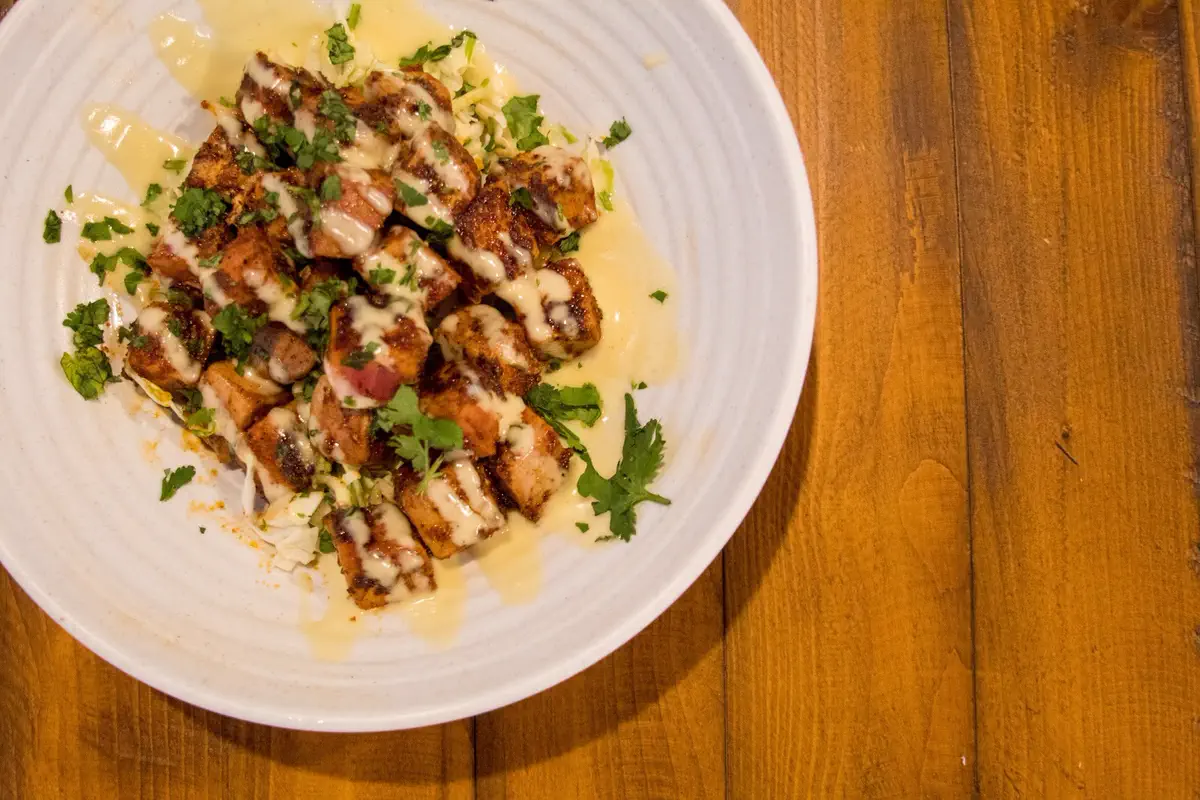 Blackened tuna bites with aioli and cilantro in a white bowl